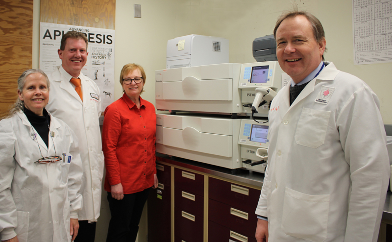Betsy Furlong, Dr. Mike DeVan, Sherry Sheldon and Dr. Bill Flegel gather near the UV Illuminator, the main hardware component of the INTERCEPT Blood System.