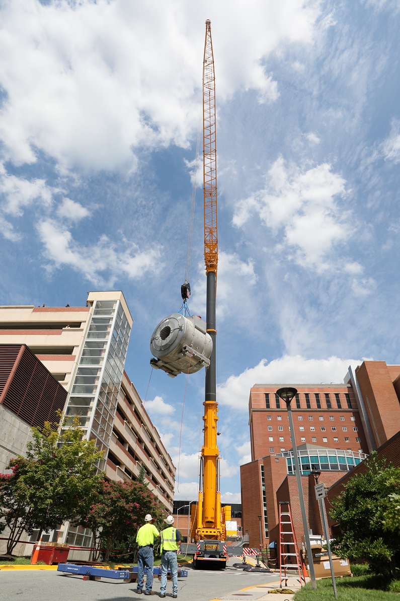 The crane lifts the magnet in the air as two men look up