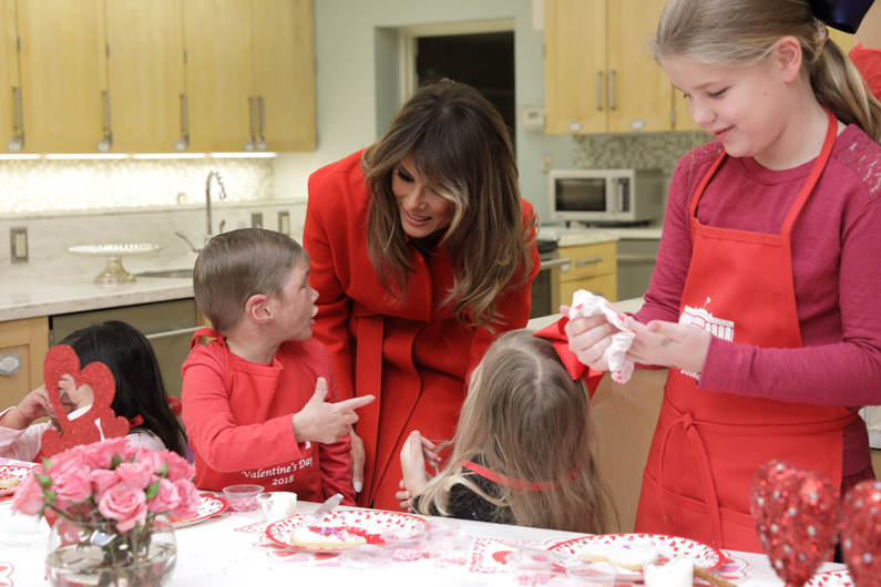 First Lady Melania Trump bends down to talk to a child while decorating cookies at The Children's Inn at NIH