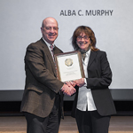 Dr. James Gilman stands with Alba C. Murphy as they smile and hold a certificate