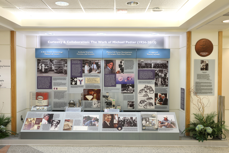 A four panel exhibit with photos, text and artifacts on NIH medical pioneers Christian Anfinsen and Michael Potter
