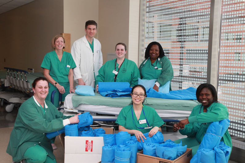 Surgical staff gather around the blankets they created