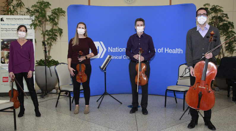 Four National Symphony Orchestra musicians stand after performing in the Clinical Center Atrium
